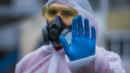 The young europeans man in protective chemical suit and respirator, outdoors. New coronavirus...