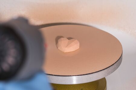 Close-up of confectioner decorates the cake with velour using the spray gun. Modern French mousse pastry dessert with chocolate velour. Heart shapeの写真素材