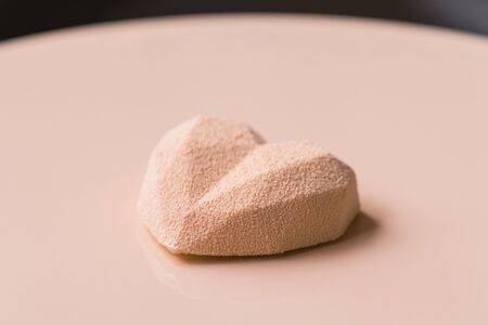 Close-up of confectioner decorates the cake with velour using the spray gun. Modern French mousse pastry dessert with chocolate velour. Heart shapeの写真素材