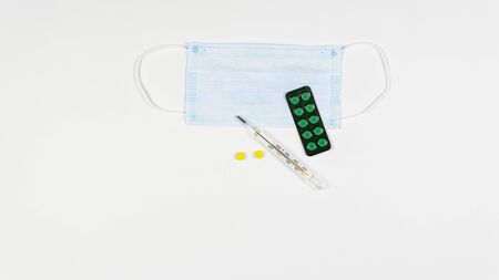 Protective medicine mask, antiseptic, thermometer and pills, flat lay. Concept of doctor table and health care. Top view, copy spaceの写真素材