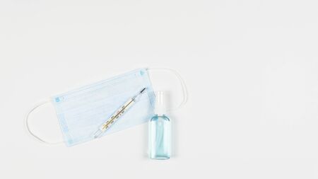 Protective medicine mask, antiseptic, thermometer and pills, flat lay. Concept of doctor table and...