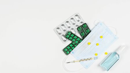 Protective medicine mask, antiseptic, thermometer and pills, flat lay. Concept of doctor table and...