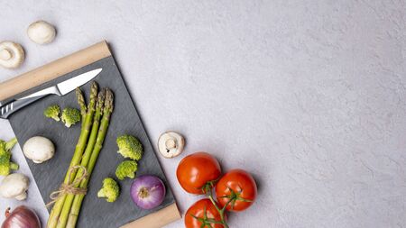 Group of organic fresh vegetables - green asparagus, broccoli, mushrooms on grey background, flat lay. Concept of  healthy vegetarian food, diet and home cooking. Top view, copy space.の写真素材