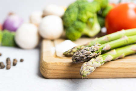 Group of organic fresh vegetables - green asparagus, broccoli, mushrooms on gray background, flat...