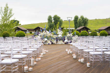Wedding reception with white, blu and violet flower and candles, outdoors. Elegant luxury wedding decoration composition on ceremony place or photo zoneの写真素材
