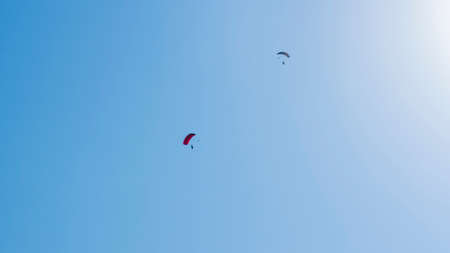 Tandem parachute jump. Silhouette of skydiver flying in blue clear sky. Concepts of extreme sport and adrenaline.の写真素材