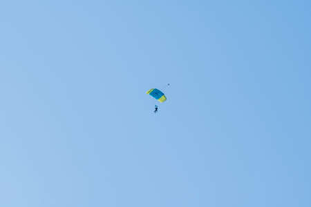 Tandem parachute jump. Silhouette of skydiver flying in blue clear sky. Concepts of extreme sport and adrenaline.の写真素材