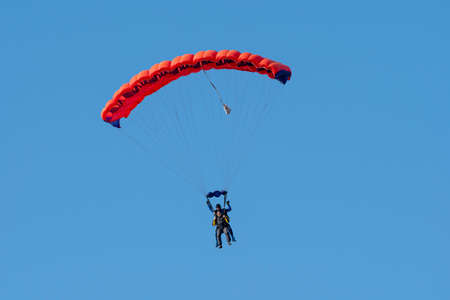Tandem parachute jump. Silhouette of skydiver flying in blue clear sky. Concepts of extreme sport and adrenaline.の写真素材