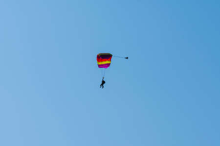 Tandem parachute jump. Silhouette of skydiver flying in blue clear sky. Concepts of extreme sport and adrenaline.の写真素材