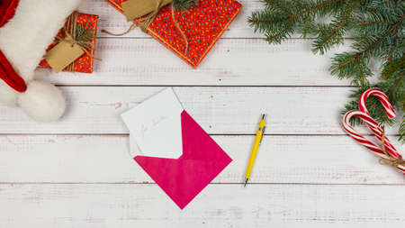 Letter to Santa Claus in an envelope on wooden background, flat lay. Christmas decorations and gift box on desk, top view. Concept of New Year eve.の写真素材
