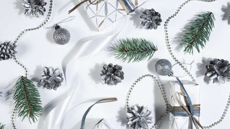 Christmas abstract background. Silver pine cones, fir tree branches and gift box spinning on white...
