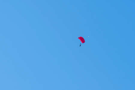 Tandem parachute jump. Silhouette of skydiver flying in blue clear sky. Concepts of extreme sport and adrenaline.の写真素材