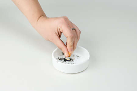 The females hand put out cigarette in ashtray on white background. Concepts of stop smoking, bad...