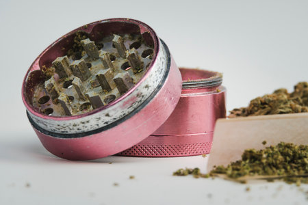 Close-up of medical marijuana buds with grinder on white background. Concepts of alternative...