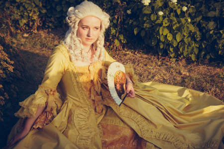 Portrait of blonde woman dressed in historical Baroque clothes with old fashion hairstyle, outdoors....
