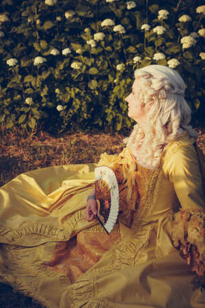 Portrait of blonde woman dressed in historical Baroque clothes with old fashion hairstyle, outdoors. Luxurious medieval dressの写真素材
