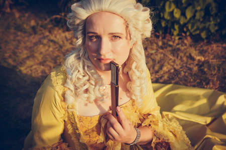 Portrait of blonde woman dressed in historical Baroque clothes with old fashion hairstyle, outdoors....