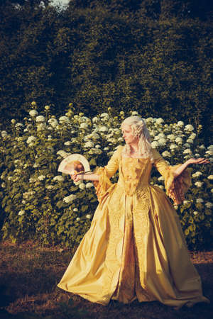 Portrait of blonde woman dressed in historical Baroque clothes with old fashion hairstyle, outdoors. Luxurious medieval dressの写真素材