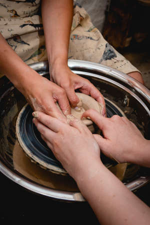 Potter working on potters wheel with clay. Process of making ceramic tableware in pottery workshop. Handicraft and art concept.の写真素材