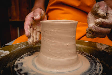 Potter working on potters wheel with clay. Process of making ceramic tableware in pottery workshop. Handicraft and art concept.の写真素材