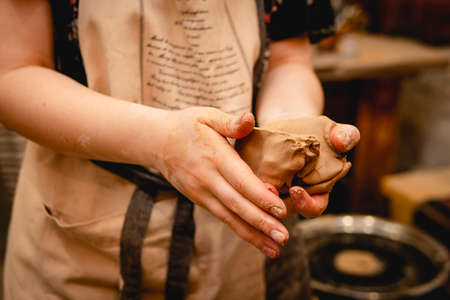 Potter working on potters wheel with clay. Process of making ceramic tableware in pottery workshop. Handicraft and art concept.の写真素材