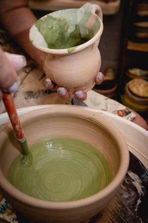 Potter working on potters wheel with clay. Process of making ceramic tableware in pottery workshop. Handicraft and art concept.の写真素材