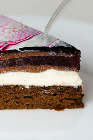 Close-up mousse cake covered black, red and white mirror glaze. French dessert. Frozen mirror icing...
