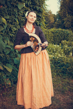 Portrait of brunette woman dressed in historical Baroque clothes with old fashion hairstyle, outdoors. Middle class medieval dressの写真素材