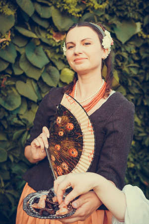 Portrait of brunette woman dressed in historical Baroque clothes with old fashion hairstyle, outdoors. Middle class medieval dressの写真素材