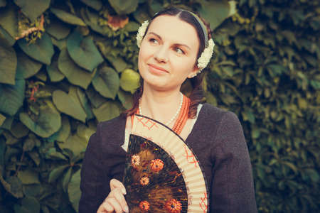 Portrait of brunette woman dressed in historical Baroque clothes with old fashion hairstyle,...