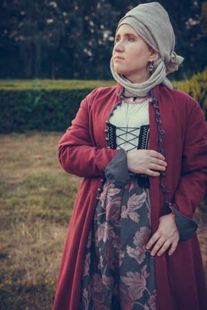 Portrait of woman dressed in historical Baroque clothes with a headscarf, outdoors. Middle class medieval dressの写真素材