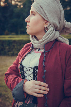 Portrait of woman dressed in historical Baroque clothes with a headscarf, outdoors. Middle class medieval dressの写真素材