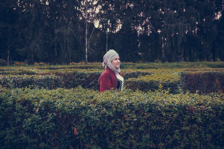Portrait of woman dressed in historical Baroque clothes with a headscarf, outdoors. Middle class...