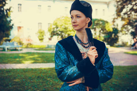 Portrait of woman dressed in blue historical Baroque clothes with old fashion hairstyle, outdoors. Luxurious medieval dressの写真素材