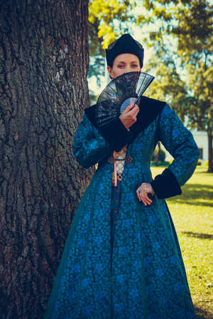 Portrait of woman dressed in blue historical Baroque clothes with old fashion hairstyle, outdoors. Luxurious medieval dressの写真素材
