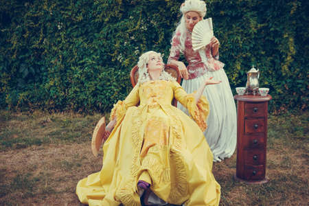 Portrait of two blonde woman dressed in historical Baroque clothes with old fashion hairstyle, outdoors. Luxurious medieval dressの写真素材
