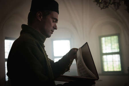 Portrait of a man in a medieval costume. A scribe writes on a red table. Retro style and historical clothing conceptsの写真素材