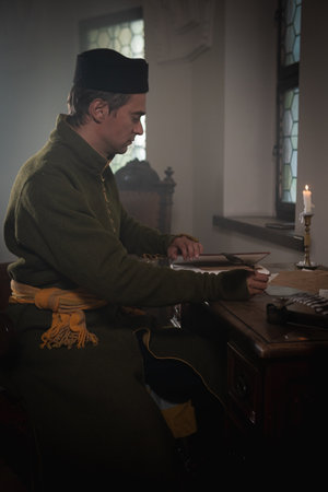 Portrait of a man in a medieval costume. A scribe writes on a red table. Retro style and historical clothing conceptsの写真素材