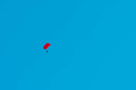 Tandem parachute jump. Silhouette of skydiver flying in blue clear sky. Concepts of extreme sport and adrenaline.の写真素材