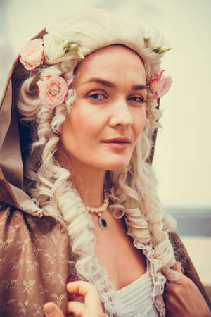 Portrait of blonde woman dressed in historical Baroque clothes with old fashion hairstyle, outdoors. Luxurious medieval dressの写真素材