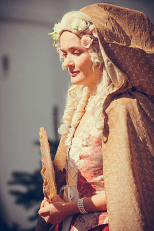 Portrait of blonde woman dressed in historical Baroque clothes with old fashion hairstyle, outdoors....