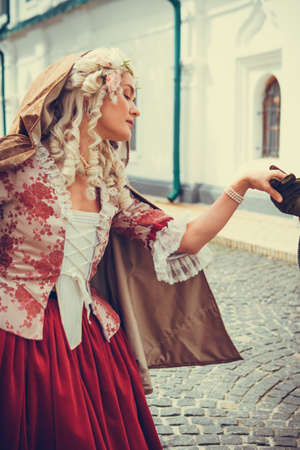 Portrait of blonde woman dressed in historical Baroque clothes with old fashion hairstyle, outdoors. Luxurious medieval dressの写真素材