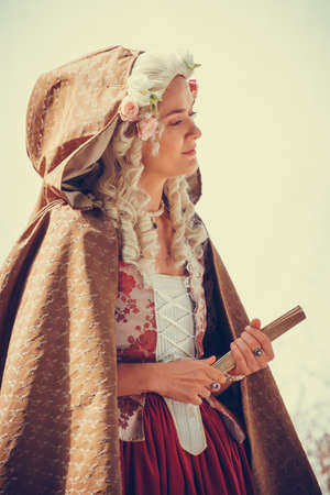 Portrait of blonde woman dressed in historical Baroque clothes with old fashion hairstyle, outdoors. Luxurious medieval dressの写真素材