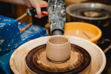 Potter working on potters wheel with clay. Process of making ceramic tableware in pottery workshop. Handicraft and art concept.の写真素材