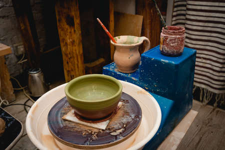 Potter working on potters wheel with clay. Process of making ceramic tableware in pottery workshop. Handicraft and art concept.の写真素材