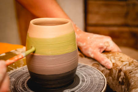 Potter working on potters wheel with clay. Process of making ceramic tableware in pottery workshop. Handicraft and art concept.の写真素材