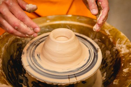 Potter working on potters wheel with clay. Process of making ceramic tableware in pottery workshop. Handicraft and art concept.の写真素材
