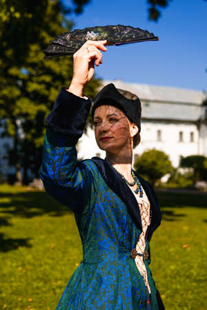 Portrait of woman dressed in blue historical Baroque clothes with old fashion hairstyle, outdoors. Luxurious medieval dressの写真素材