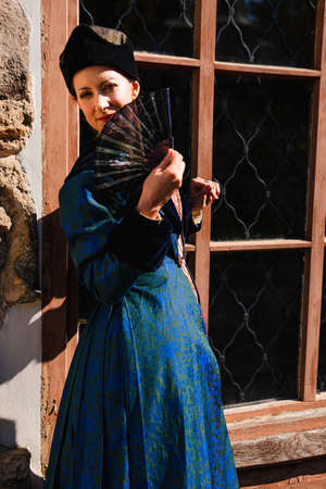 Portrait of woman dressed in blue historical Baroque clothes with old fashion hairstyle, outdoors. Luxurious medieval dressの写真素材