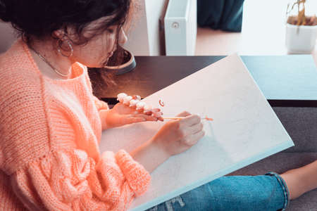 The adult woman painting by numbers, pastel colors, drawing on canvas. Concepts of leisure activity, hobby and relaxの写真素材